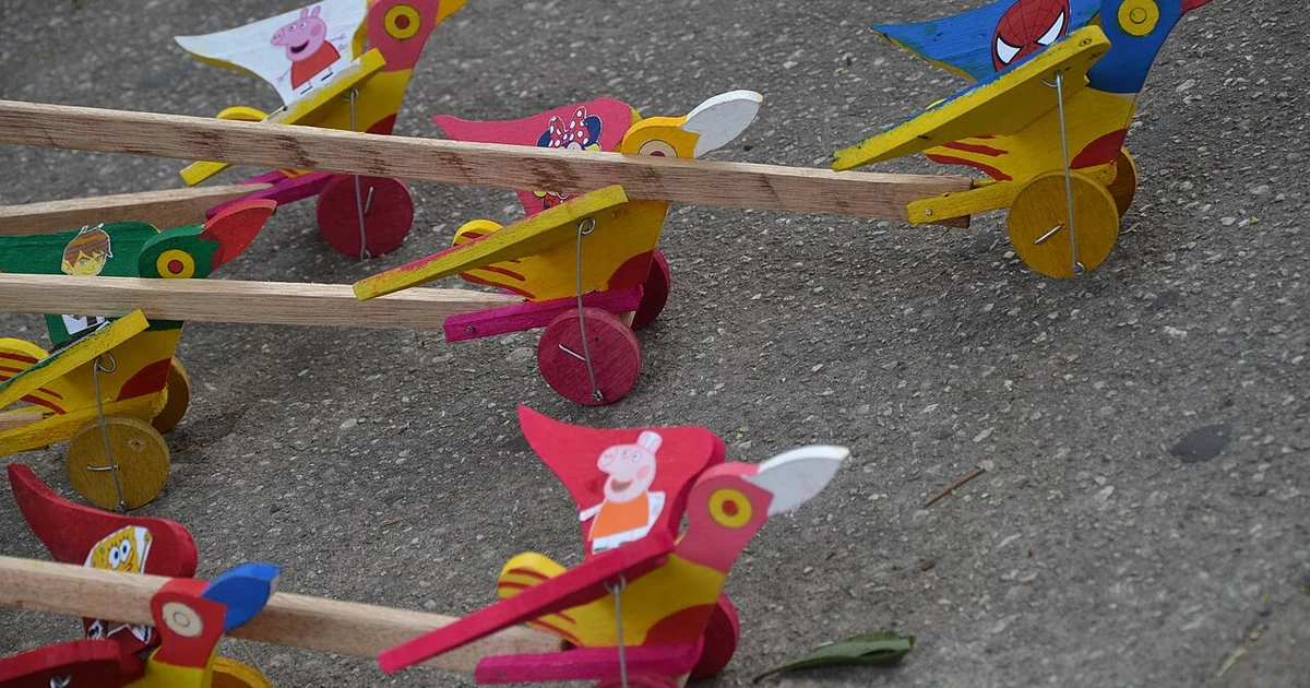 Wooden toy birds with wheels on a stick.